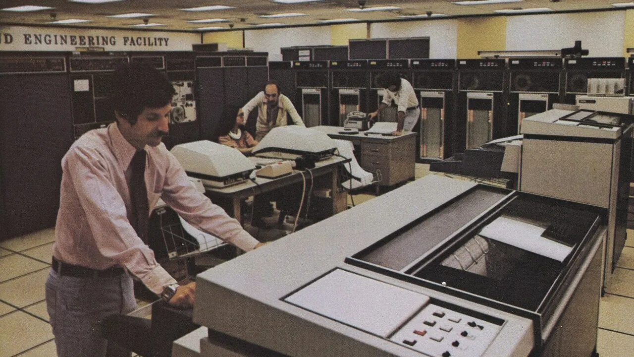 Sala de mainframe dos anos 1970 com operadores e plotador — capa sobre sistemas legados